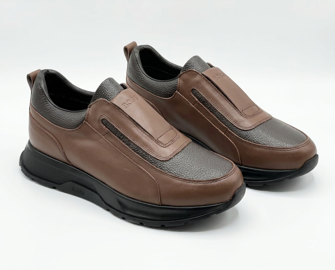 Pair of cognac brown Hugo Boss leather slip-on shoes with black soles on a plain white background