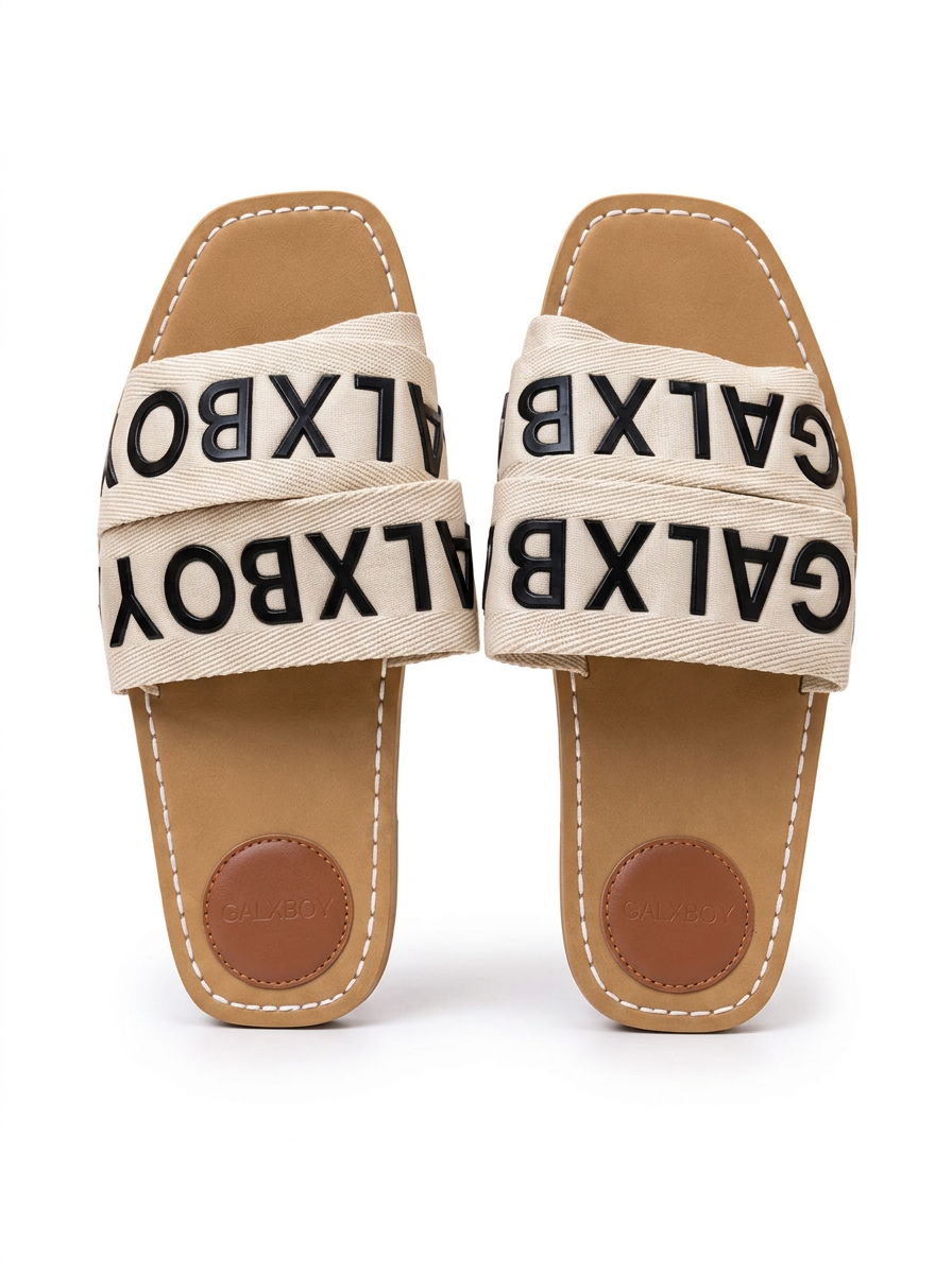 Pair of cream logo tape flat mule slides with tan footbeds and white stitching on a plain white background