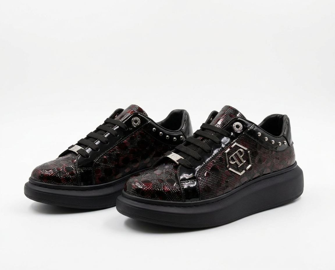 Pair of black and burgundy Philipp Plein patent platform low-top sneakers with silver studs and hexagon logo on a plain white background