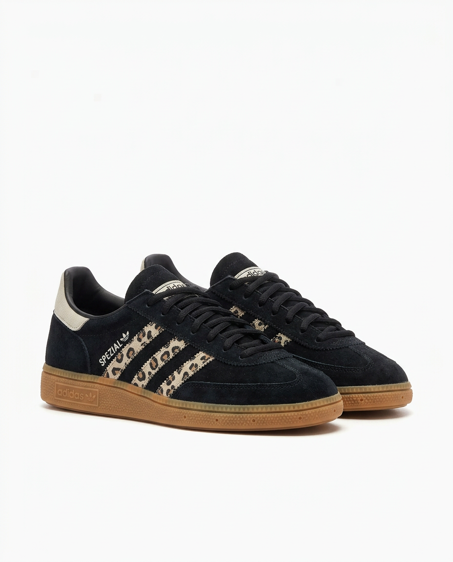 Pair of black suede adidas Handball Spezial sneakers with leopard print stripes and gum sole on a plain white background